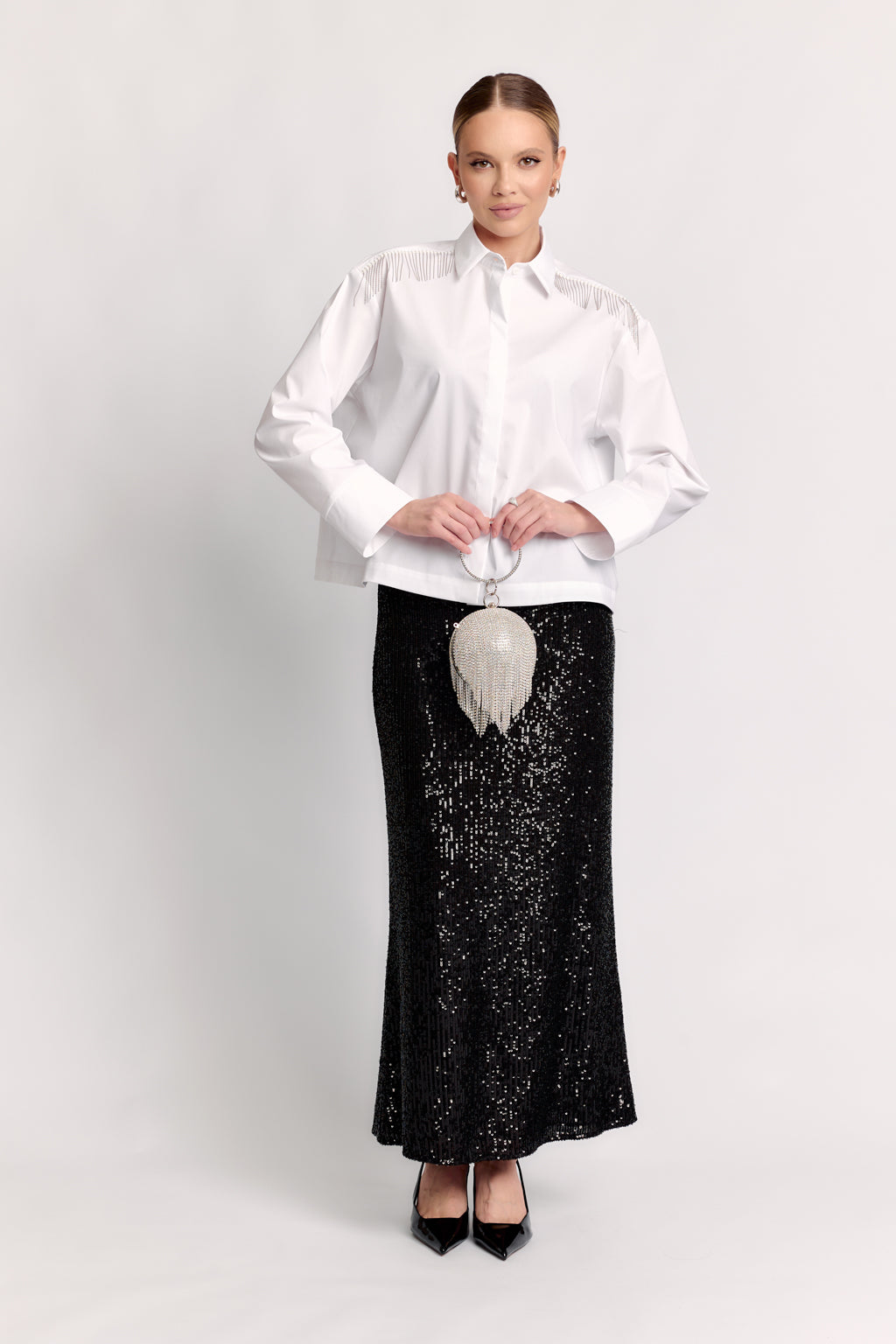 Woman wearing a white blouse and black sequin skirt on a white background