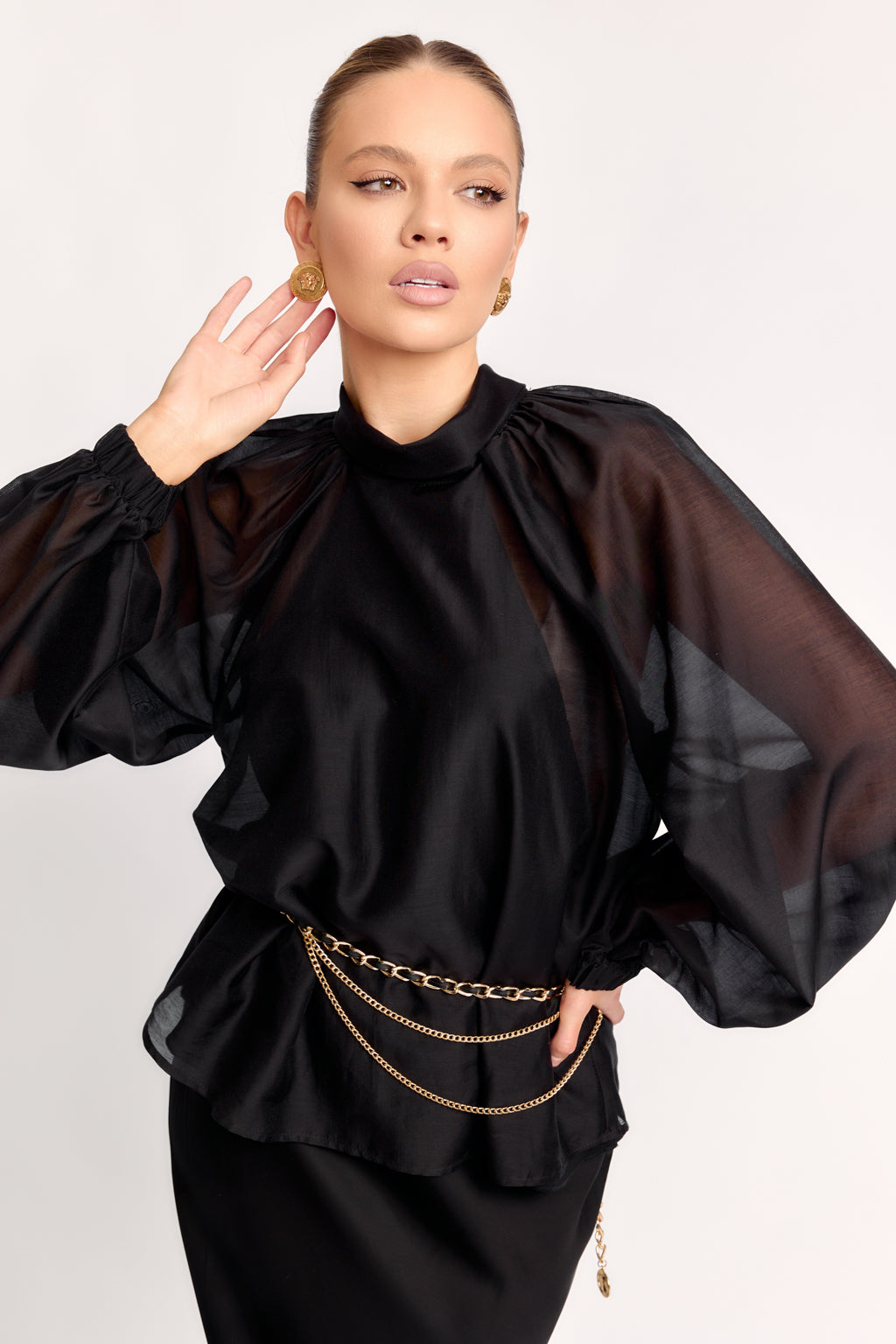 Woman wearing a black outfit with sheer sleeves on a white background