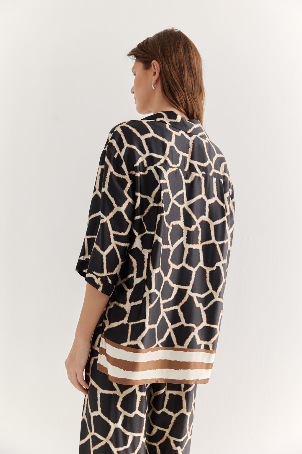 Person wearing a black and beige patterned outfit on a white background