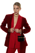 Woman wearing a red suit with a black handbag on a white background