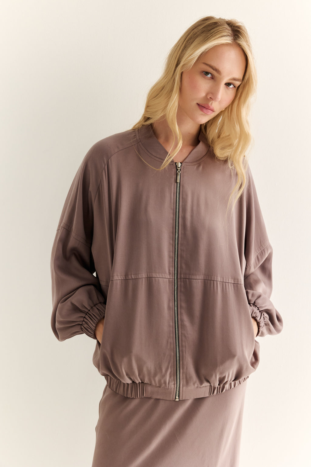 Woman wearing a brown tracksuit against a plain background