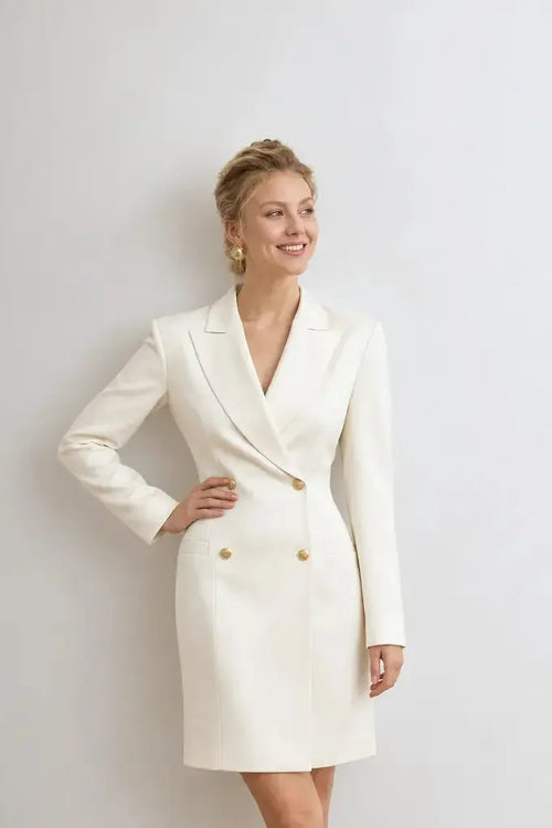 AYRA Store beautiful woman standing wearing  milk-colored double-breasted sculptural luxury jacket dress with architectural shoulders and hourglass silhouette