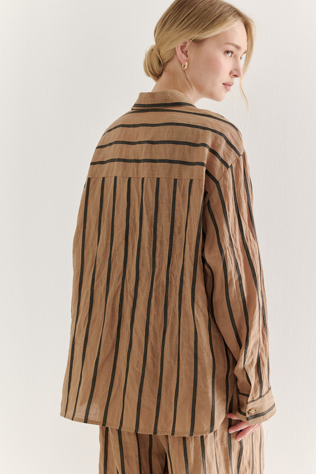 Woman wearing a brown striped shirt and pants on a white background