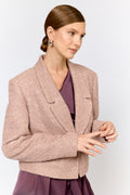 Woman wearing a beige blazer over a purple dress on a light gray background
