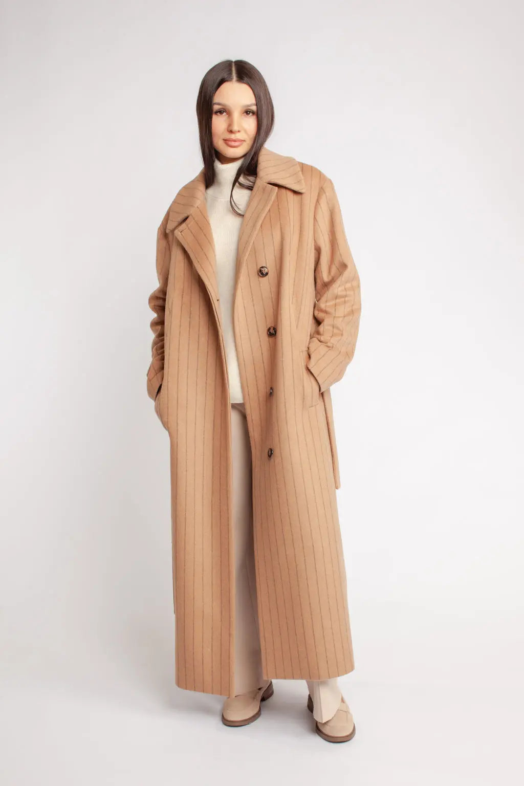 Woman wearing a long beige coat on a white background