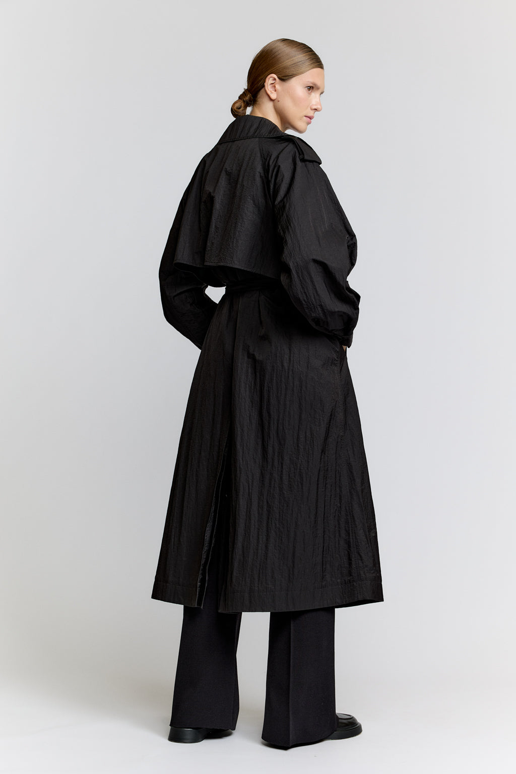 Person wearing a black coat and pants on a white background
