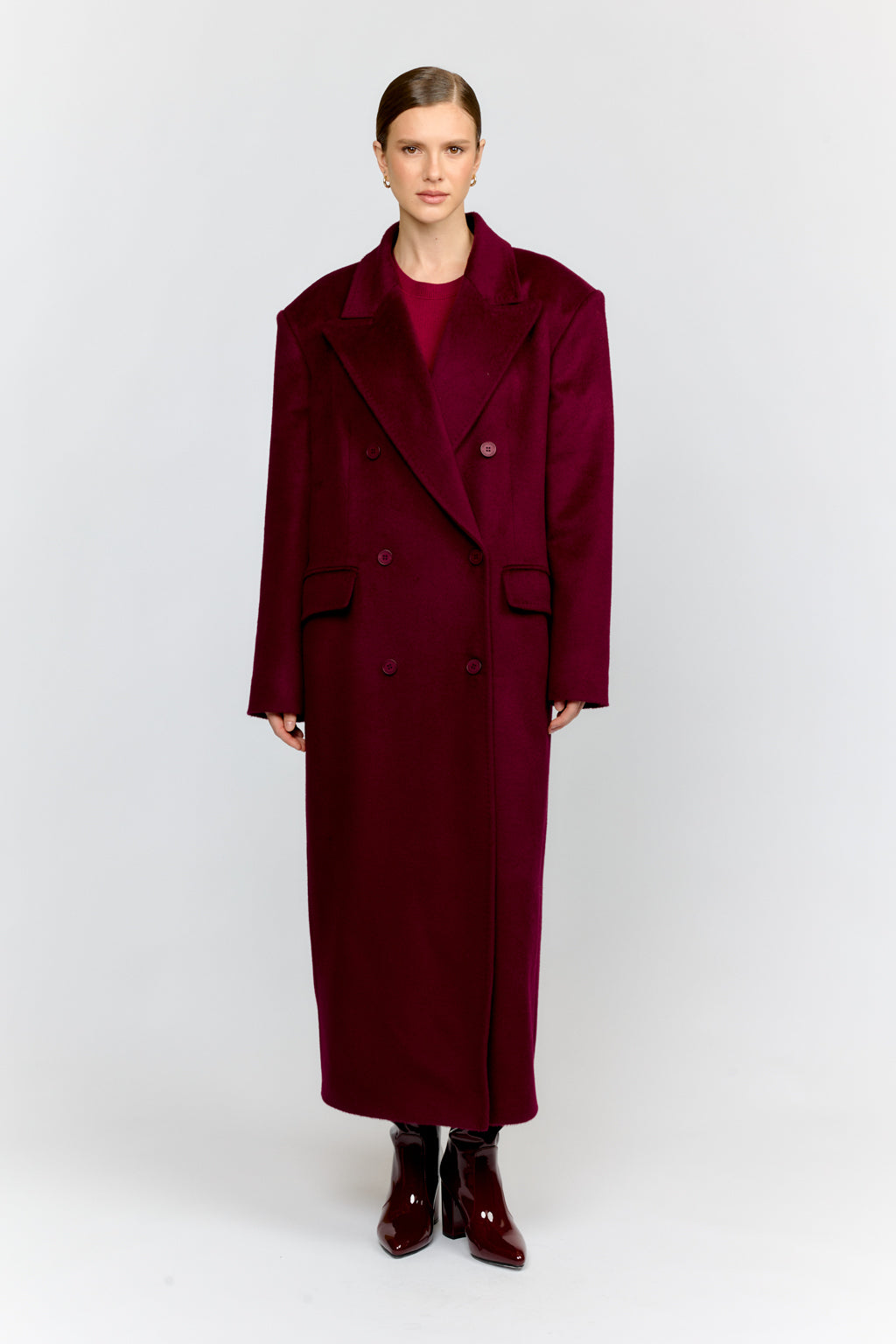 Woman wearing a long burgundy coat on a white background