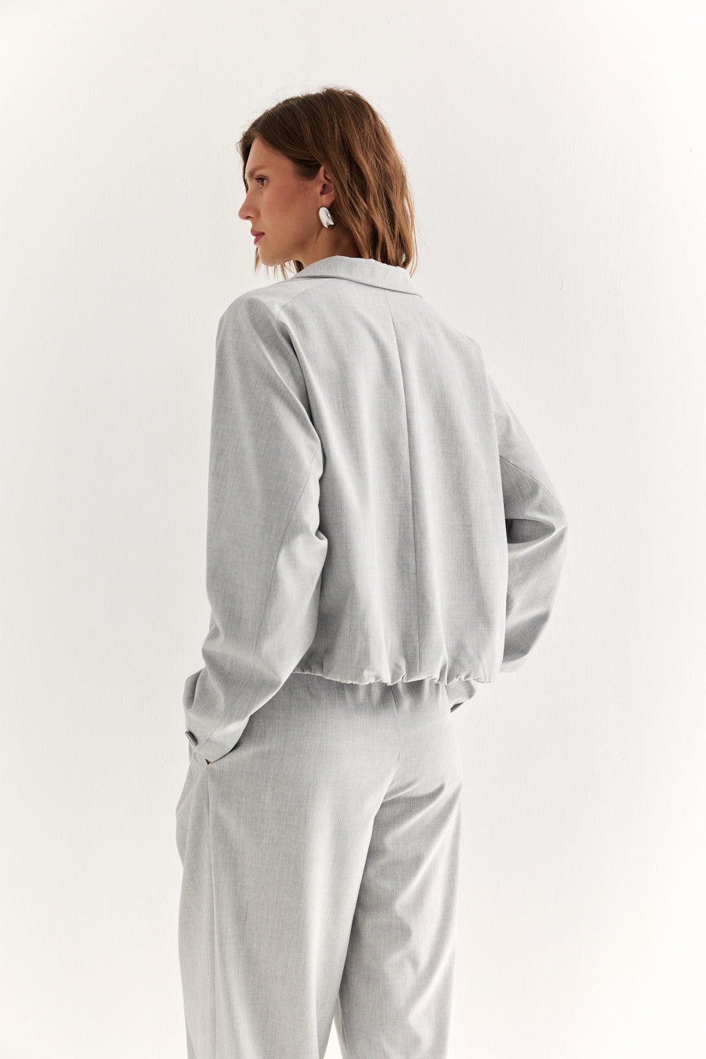 Woman wearing a light gray blouse and pants on a white background