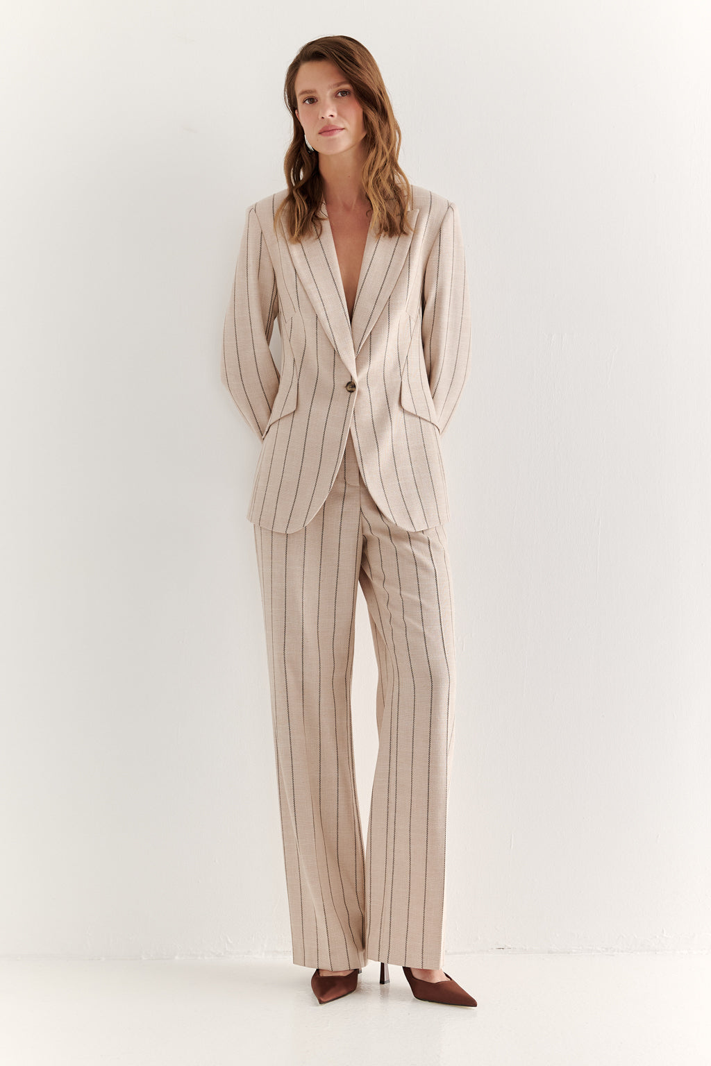 Woman wearing a beige pinstripe suit on a white background