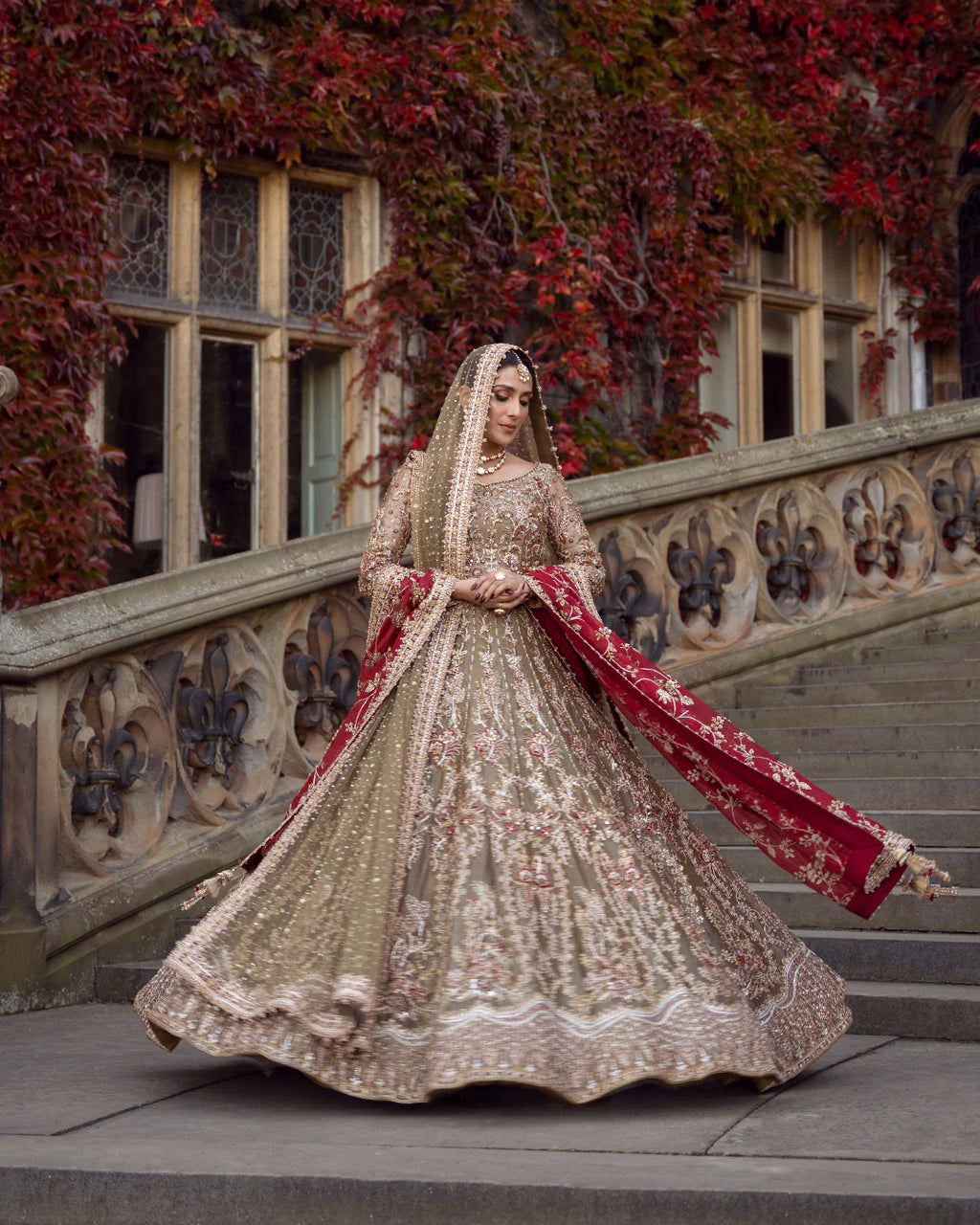 Woman in a traditional embroidered outfit standing on steps with ivy-covered walls in the background