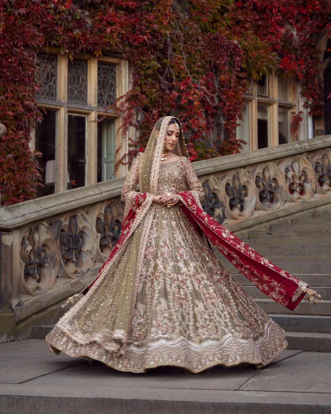 Woman in a traditional embroidered outfit standing on steps with ivy-covered walls in the background