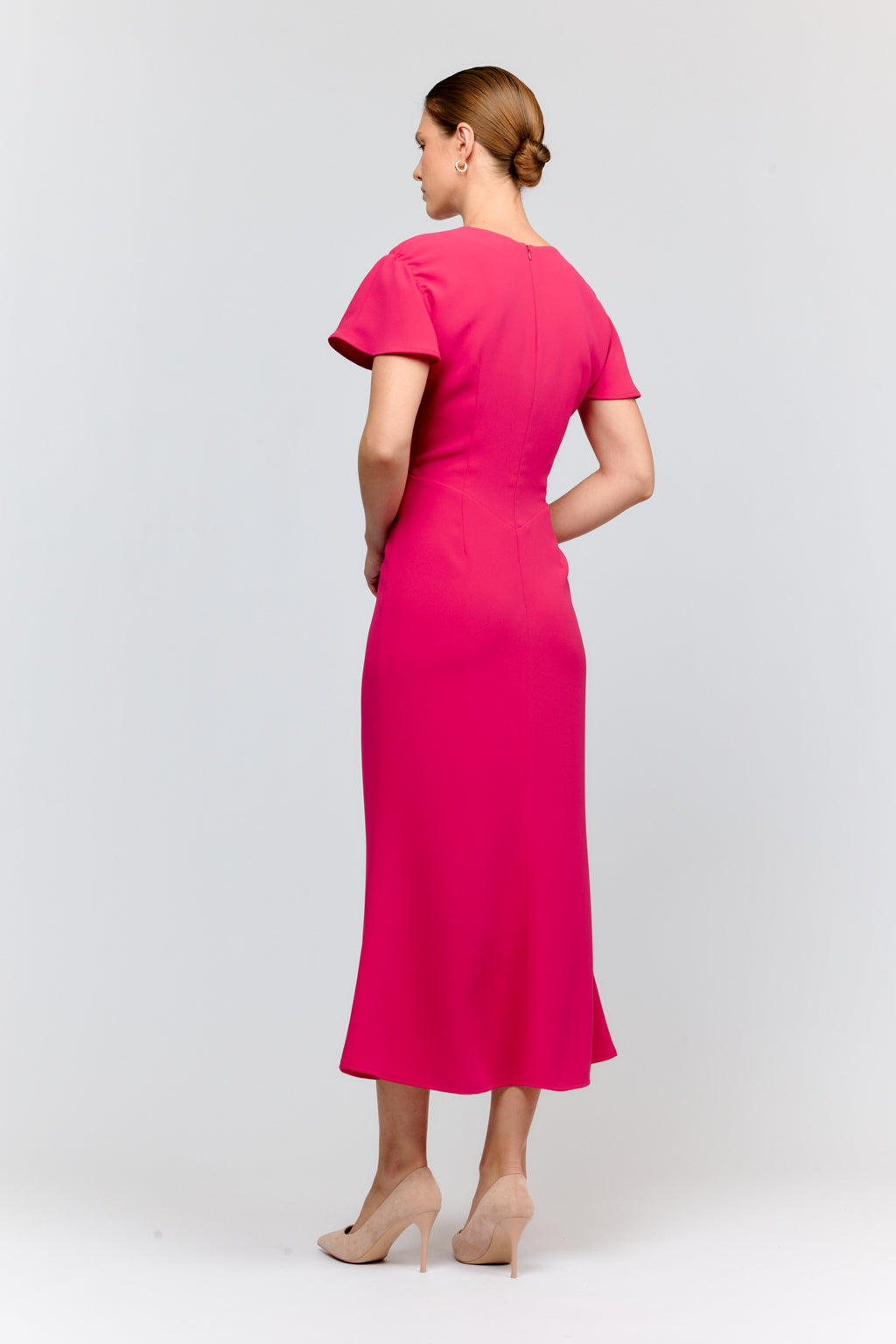 Woman wearing a bright pink dress on a white background
