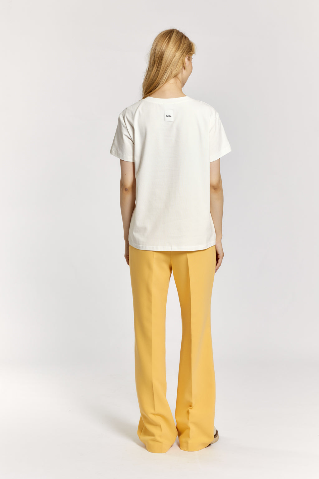 Person wearing a white t-shirt and yellow pants on a light gray background