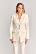 Woman wearing a cream suit on a plain background