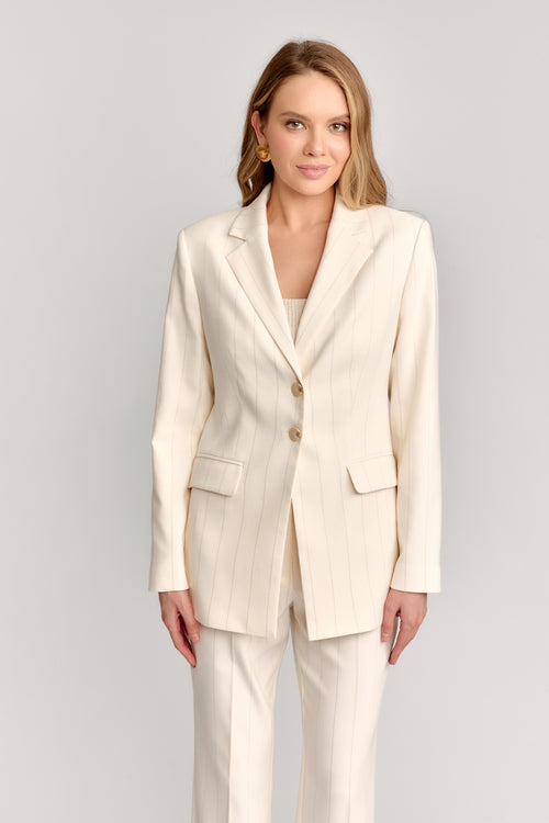 Woman wearing a cream suit on a plain background