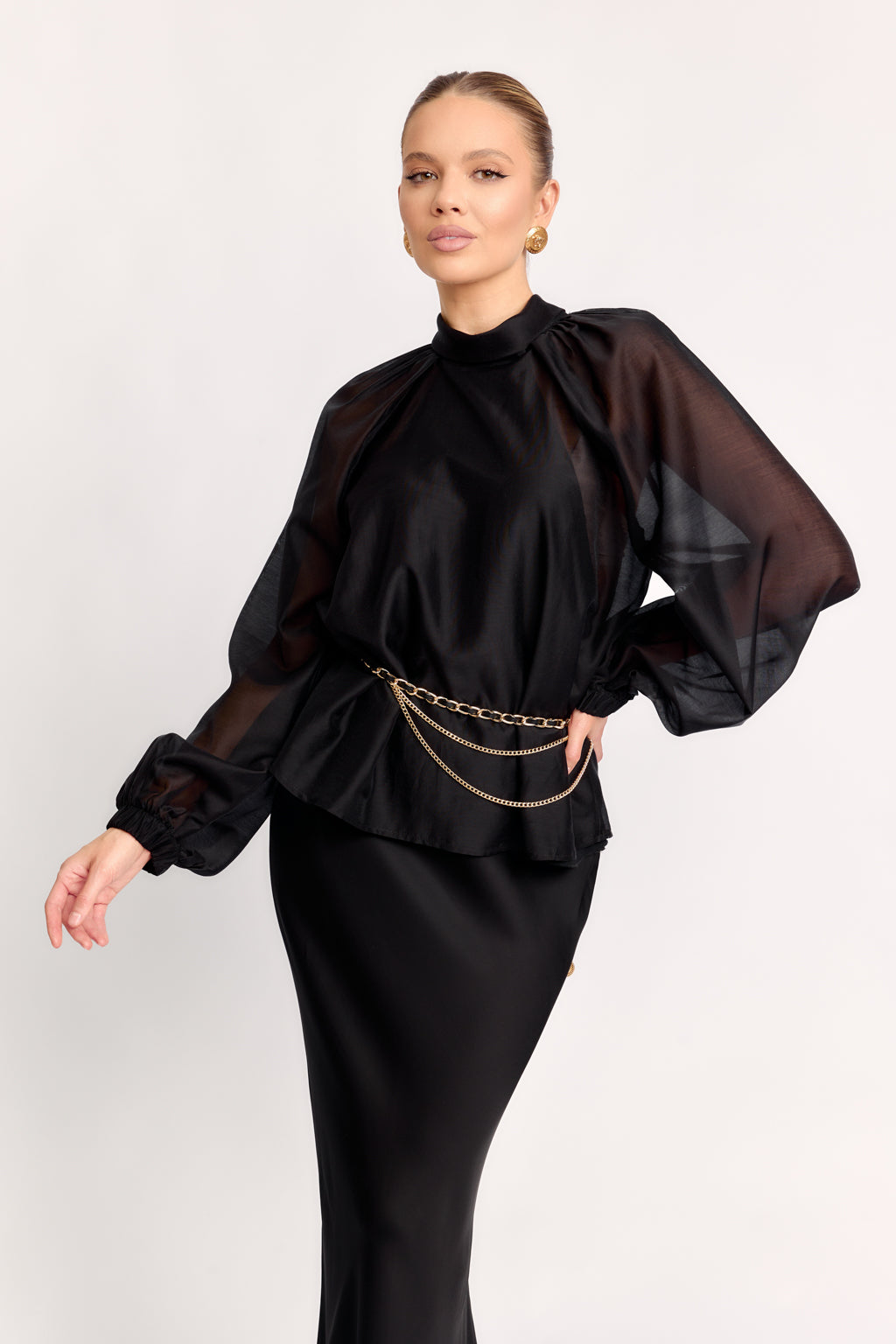 Woman wearing a black outfit with sheer sleeves on a white background