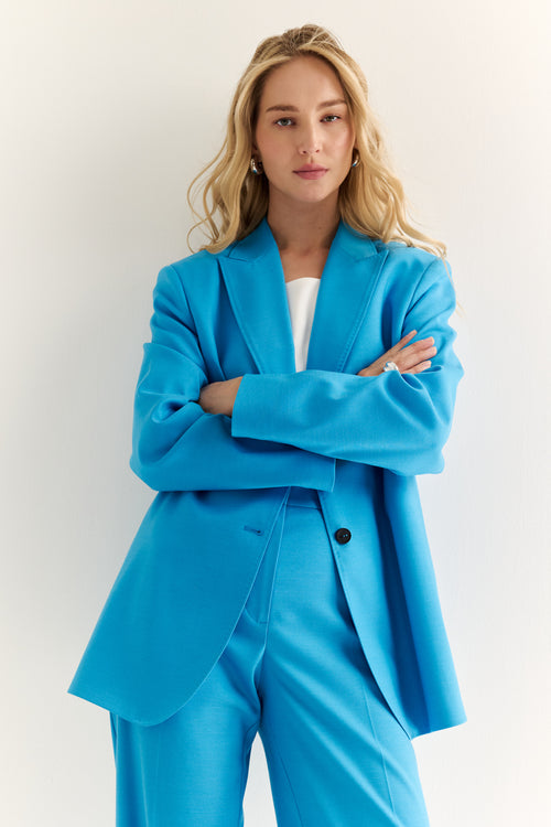 Woman wearing a bright blue suit with a white background