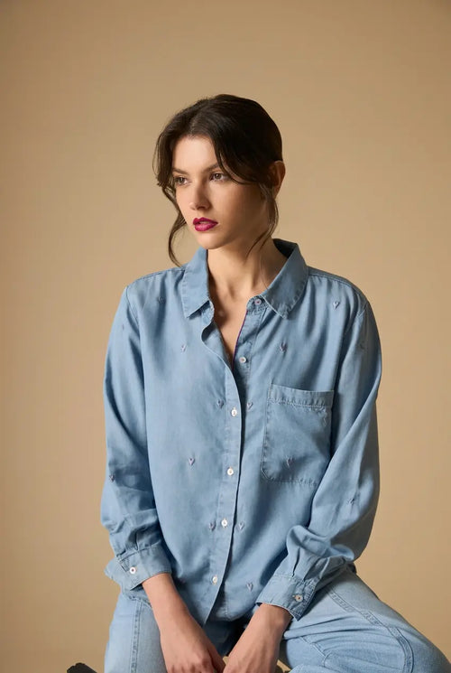 Woman wearing AYRA blue embroidered long-sleeved denim shirt with classic collar and subtle motif detailing   