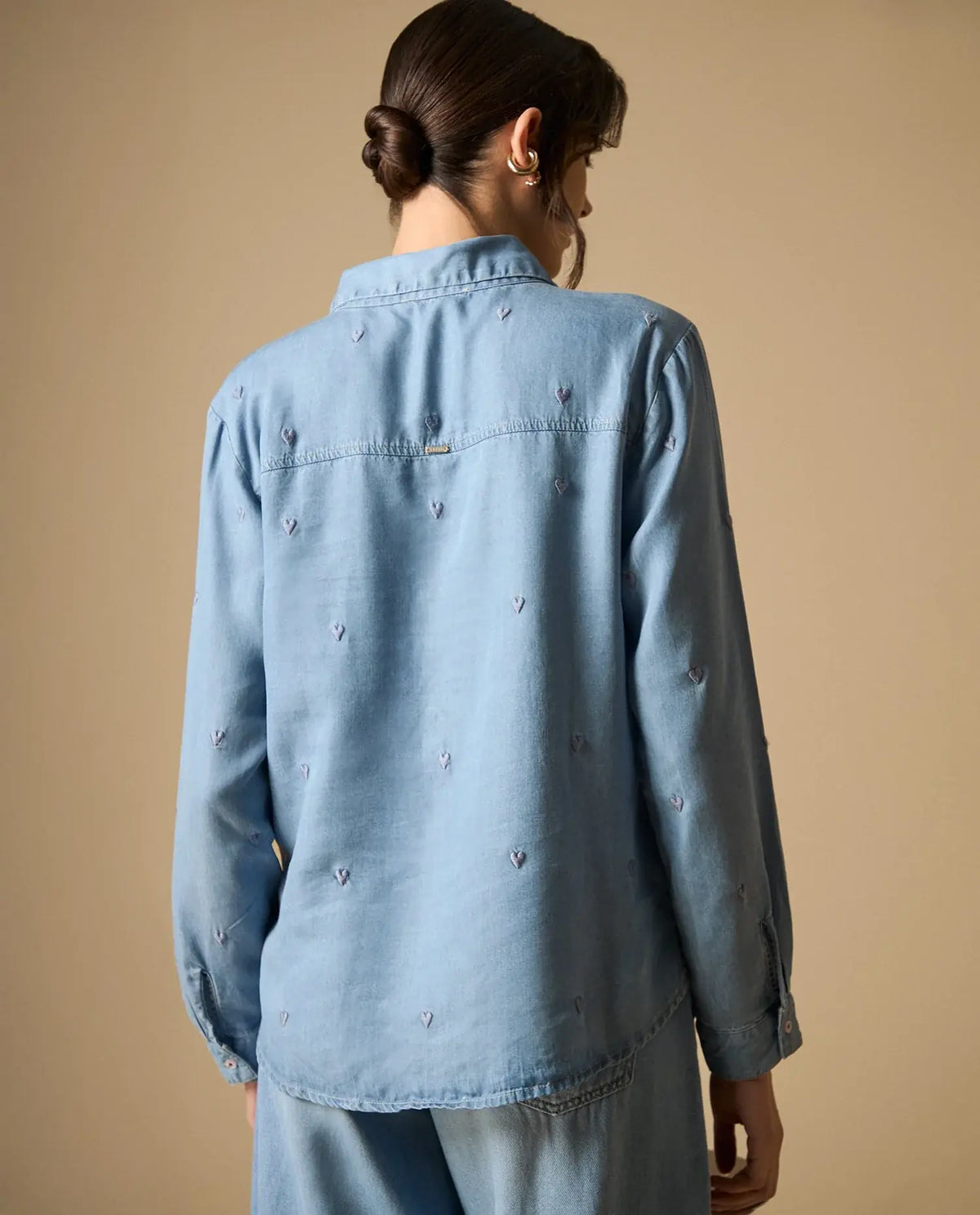 Woman wearing AYRA blue embroidered long-sleeved denim shirt with classic collar and subtle motif detailing   