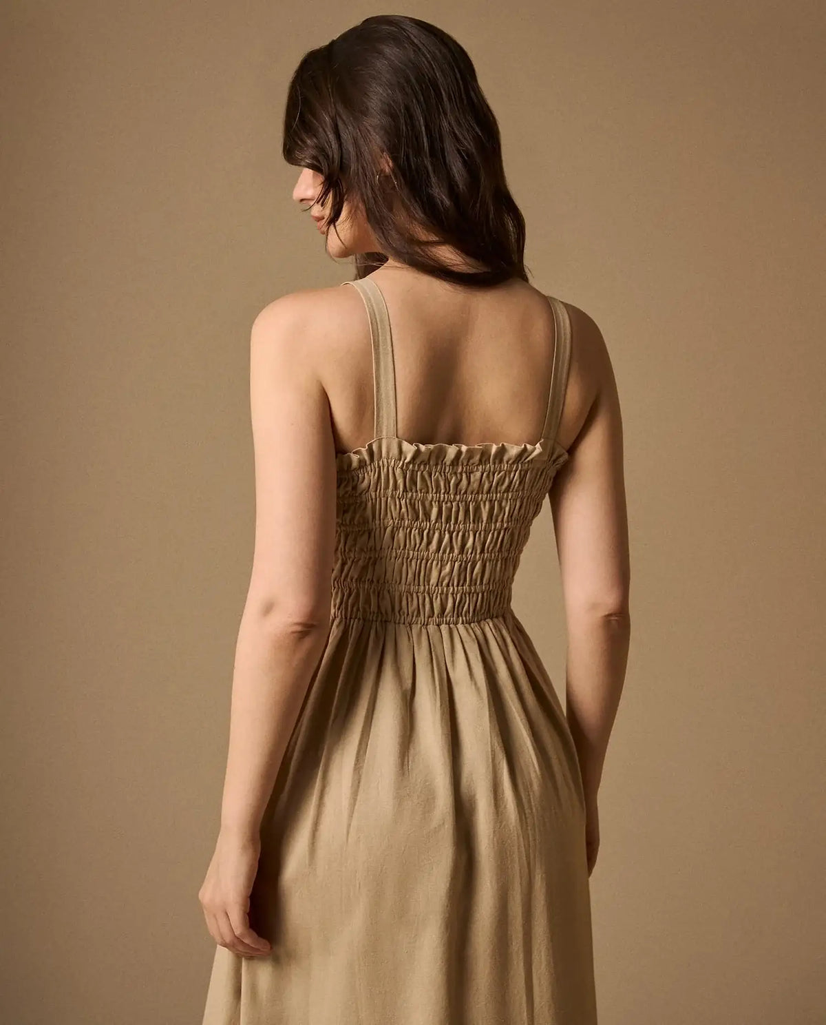 Woman wearing AYRA long beige dress featuring multicolored handcrafted floral embroidery on the structured bodice and hemline
