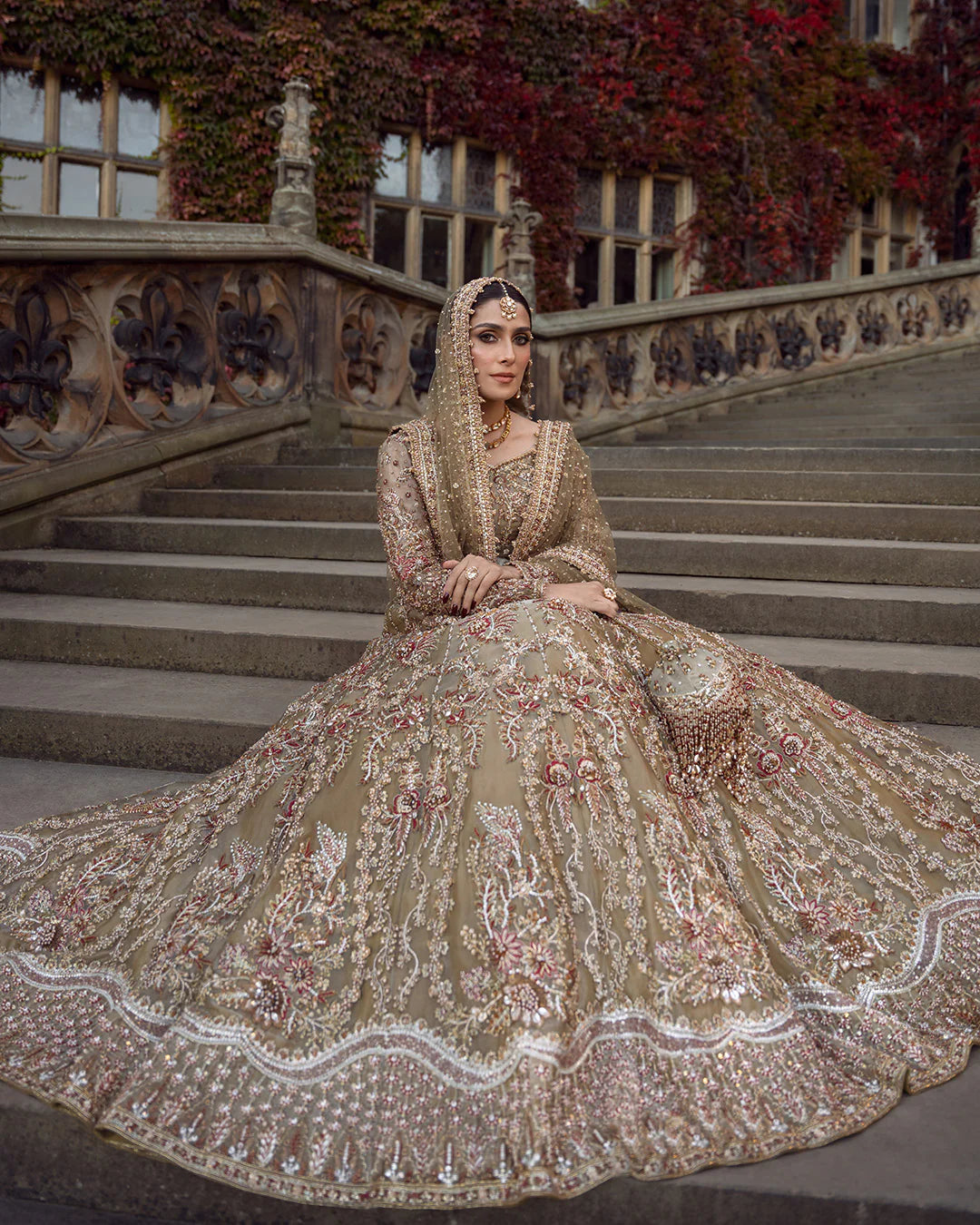 Woman in an ornate traditional outfit sitting on steps with a decorative building in the background