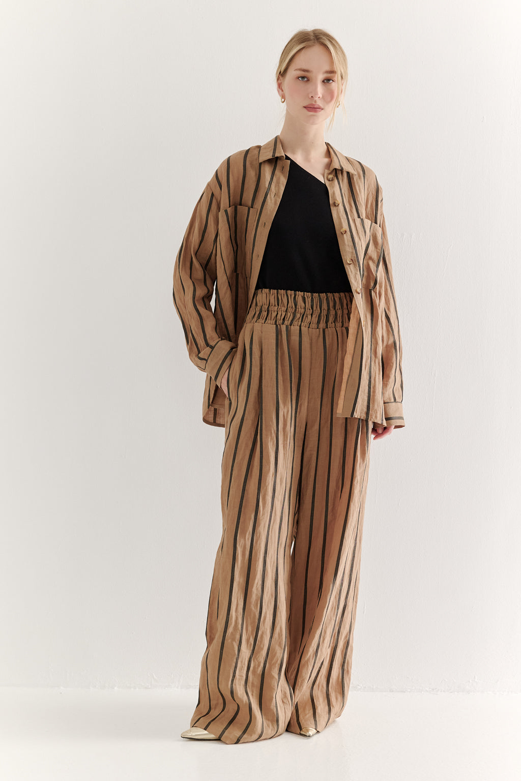 Woman wearing a striped suit with a black top on a white background