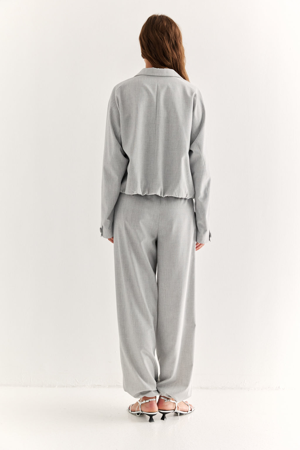 Person wearing a light gray outfit on a white background