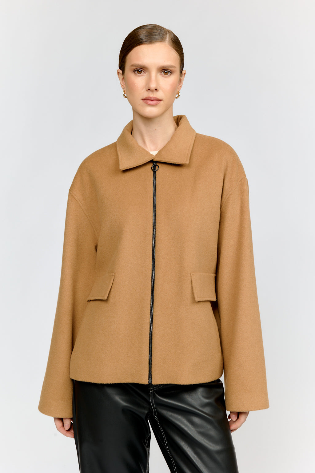 Woman wearing a tan coat on a white background