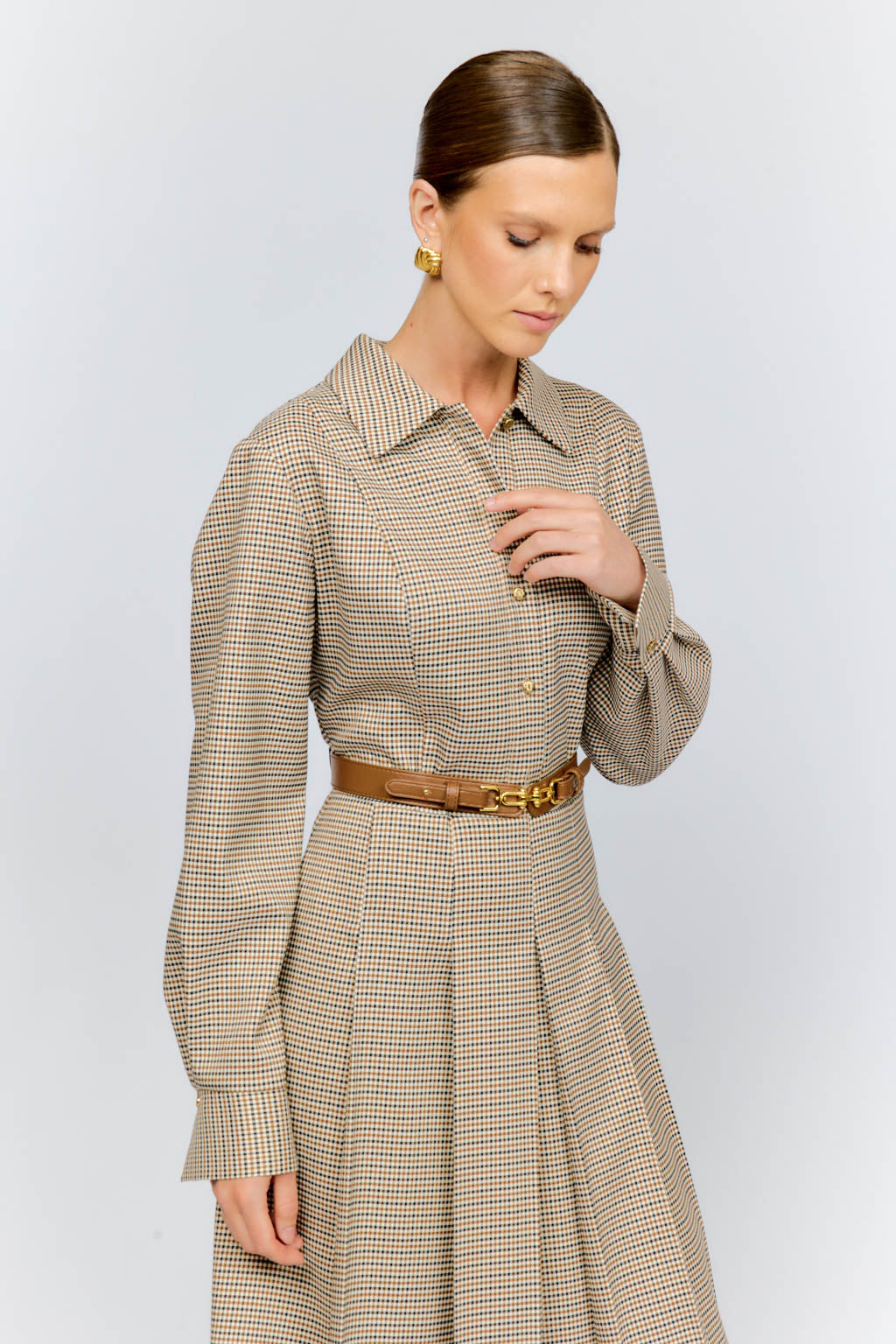 Woman wearing a beige checkered dress with a belt on a white background