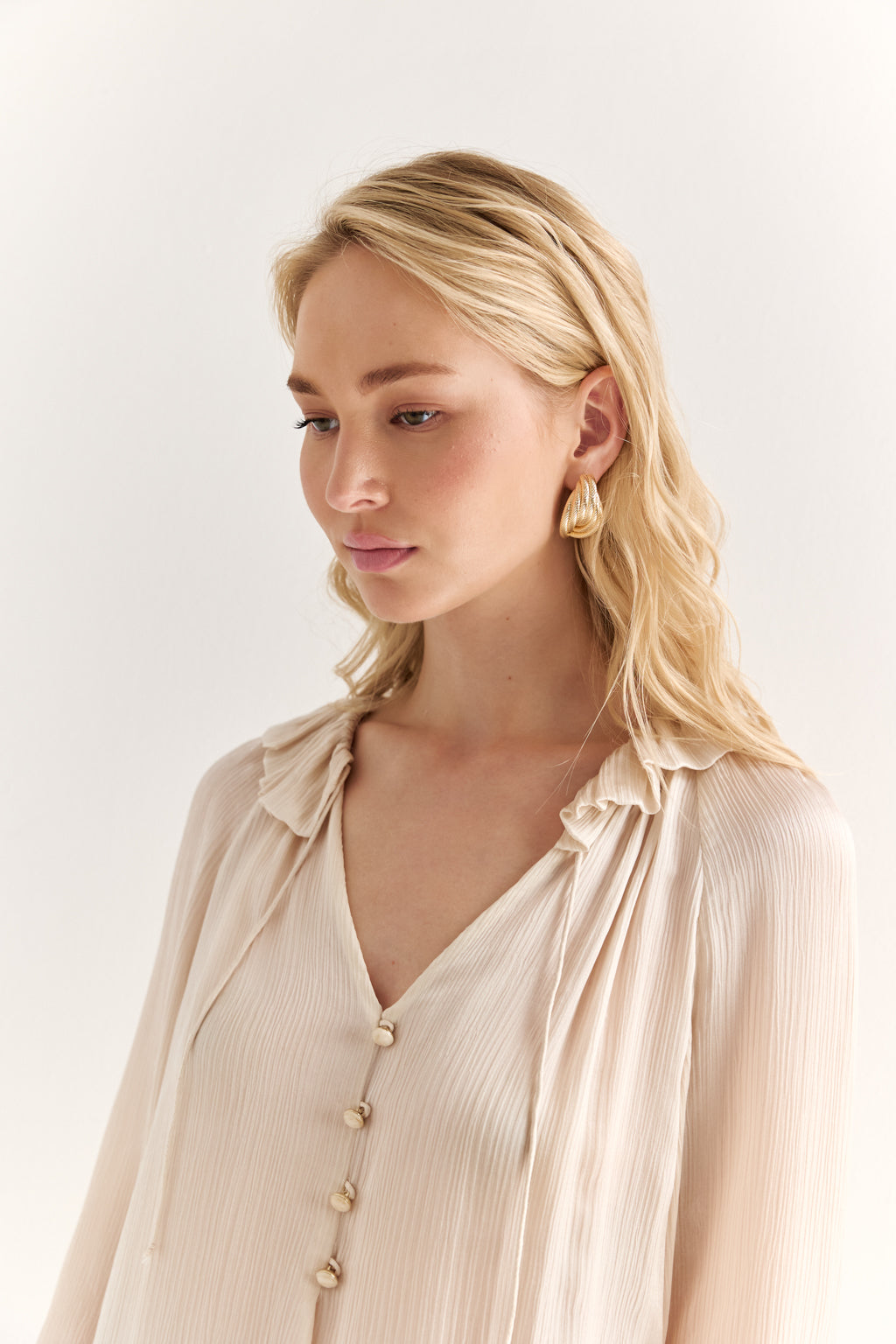 Woman wearing a beige blouse with a plain background