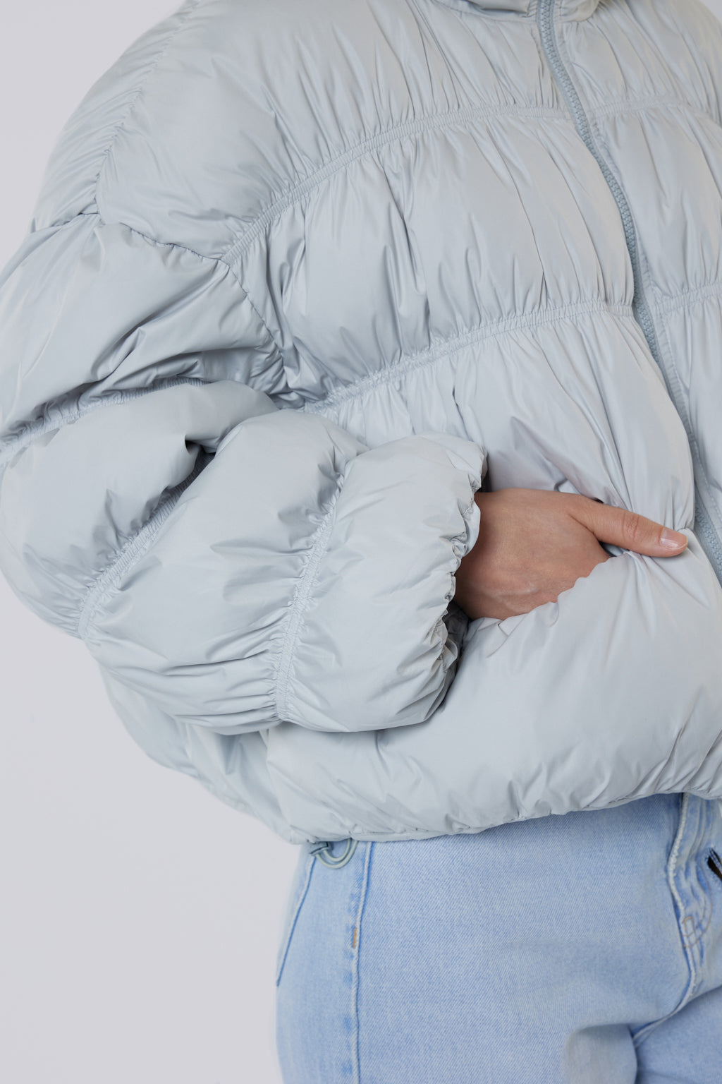 Light blue puffer jacket worn by a person on a white background