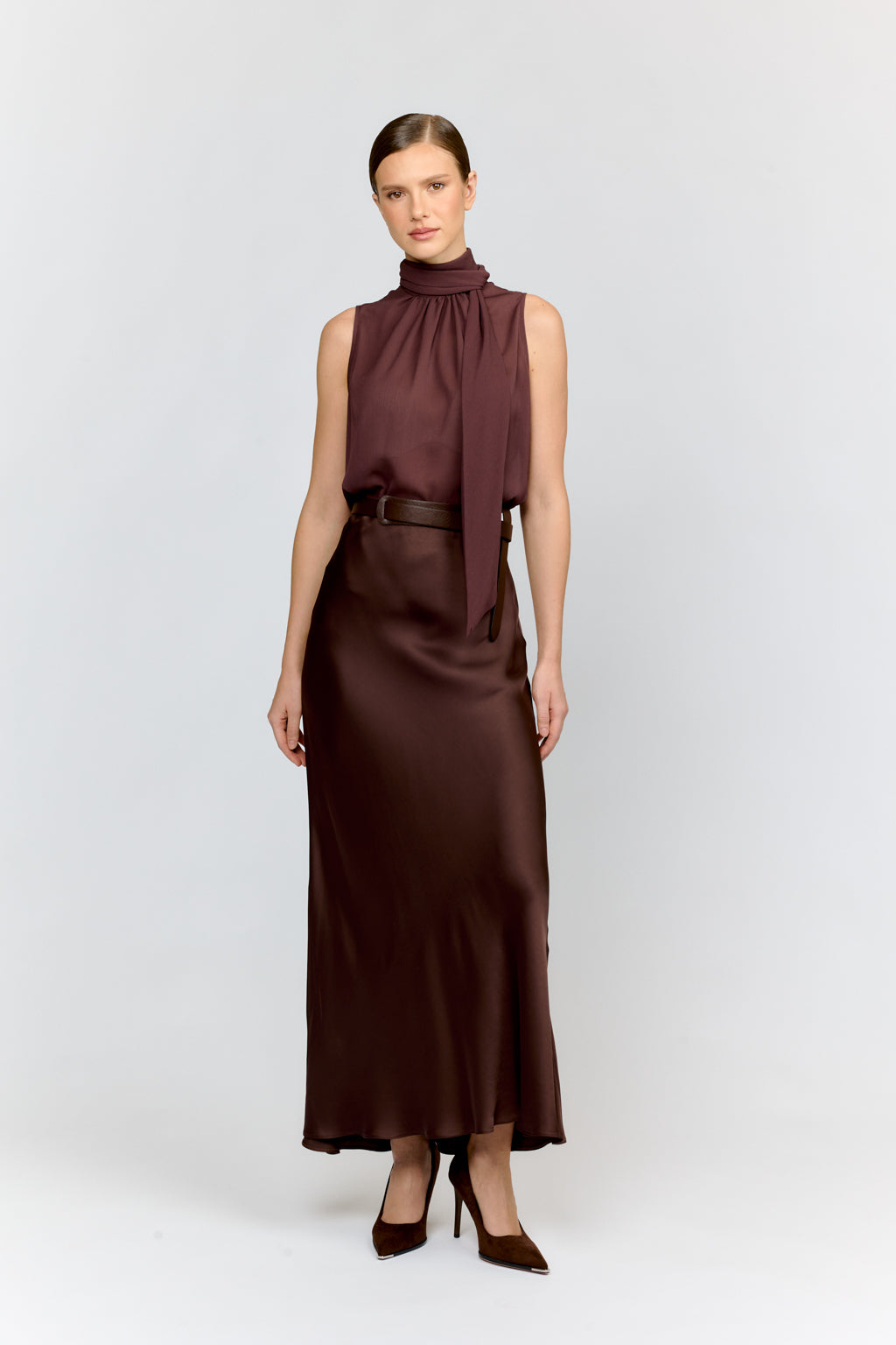 Woman wearing a brown dress with a belt on a white background
