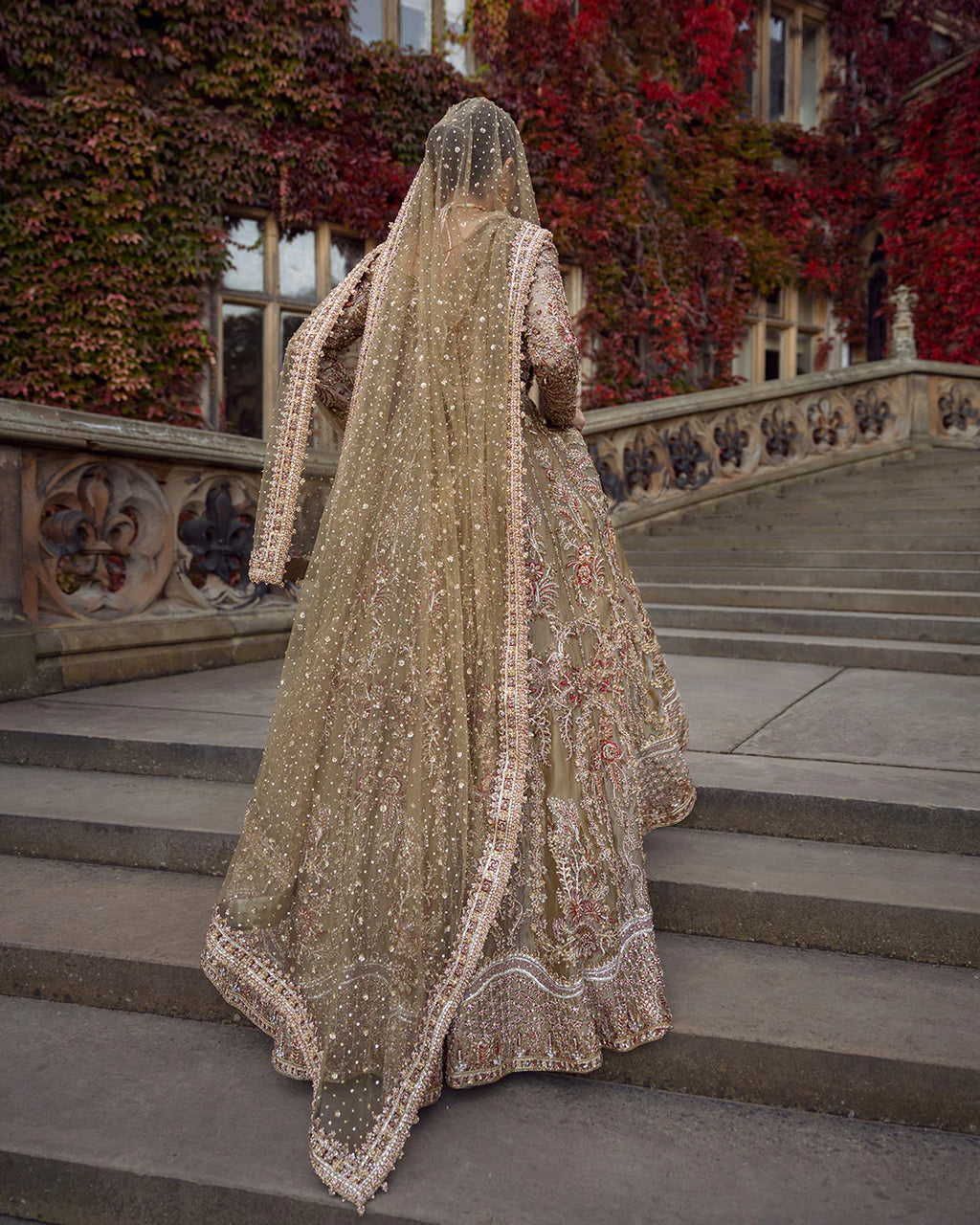 Person in a traditional embroidered outfit standing on stone steps with a decorative background