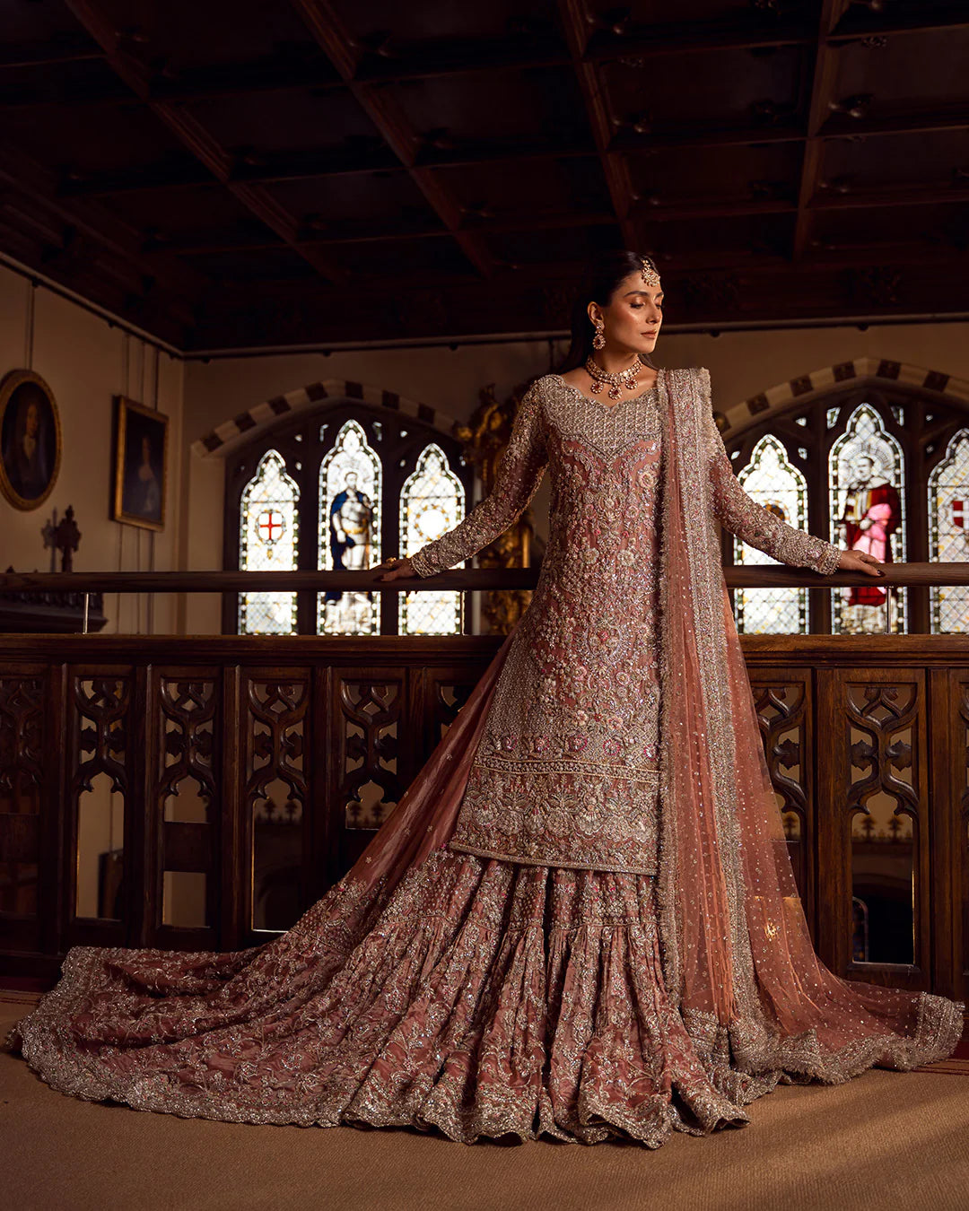 Woman in a traditional embroidered outfit standing in a room with stained glass windows.