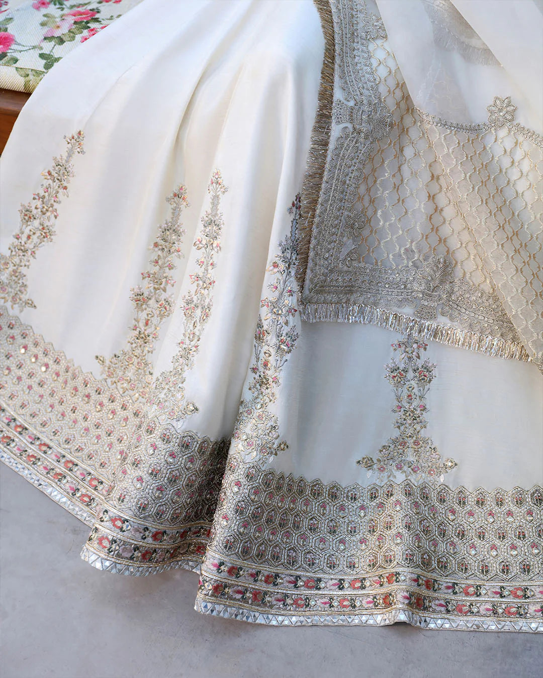Close-up of a white saree with intricate gold embroidery on a neutral background