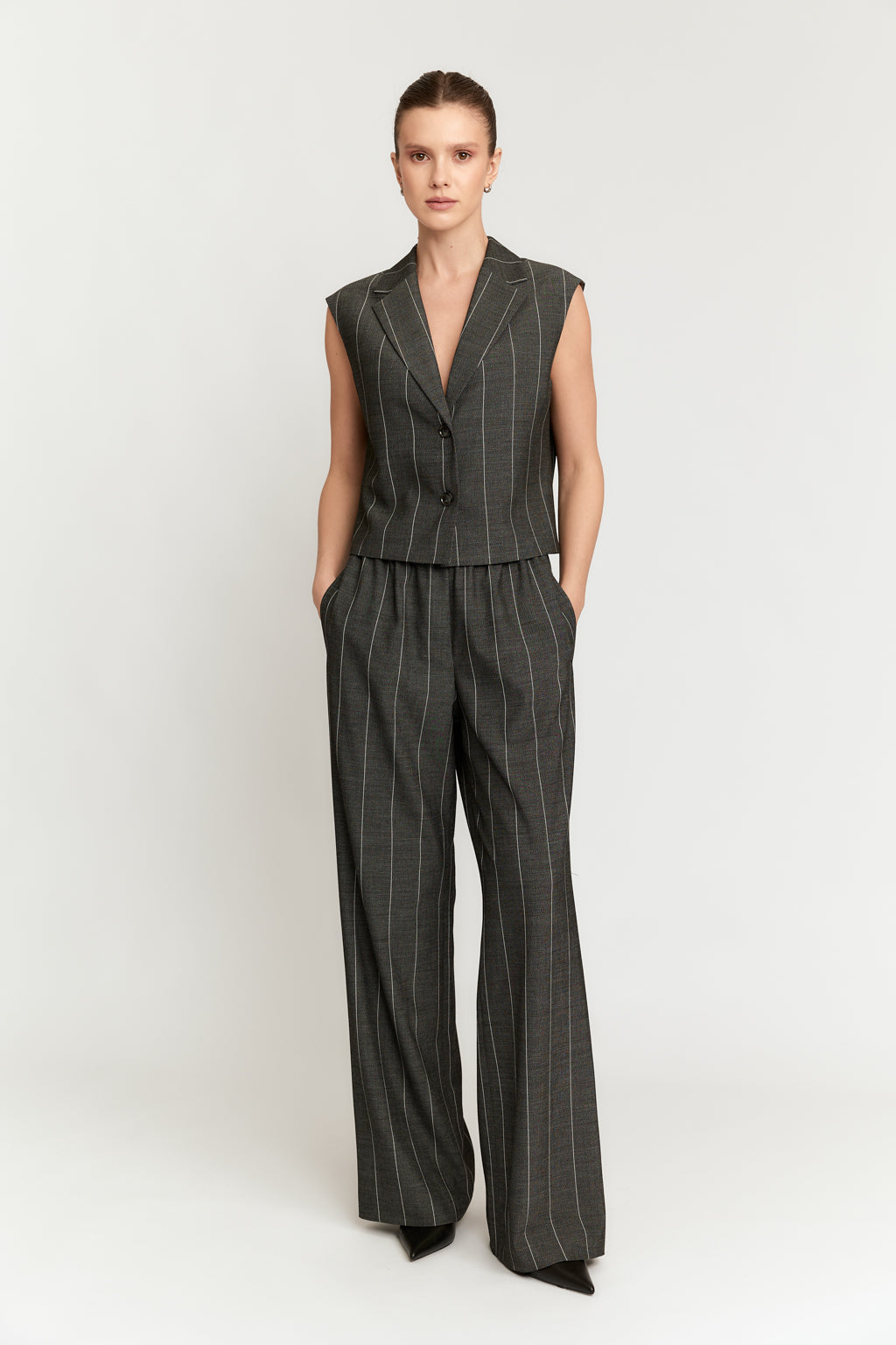 Woman wearing a pinstripe vest and pants set on a white background