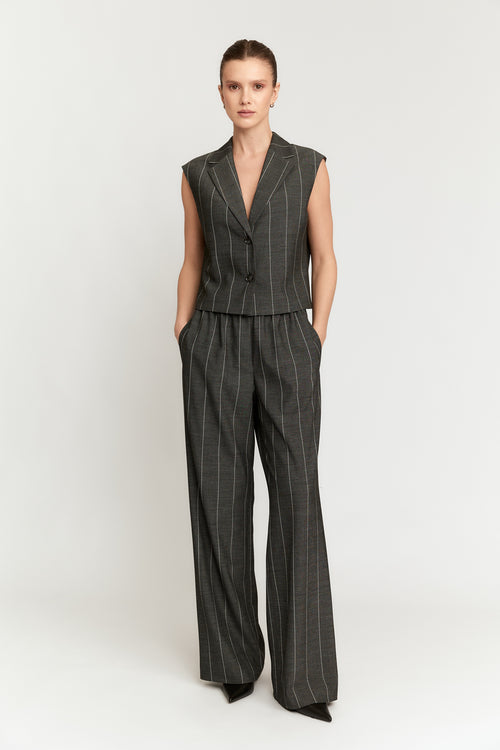 Woman wearing a pinstripe vest and pants set on a white background