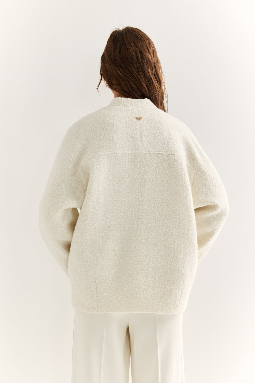 Person wearing a cream-colored cardigan on a white background