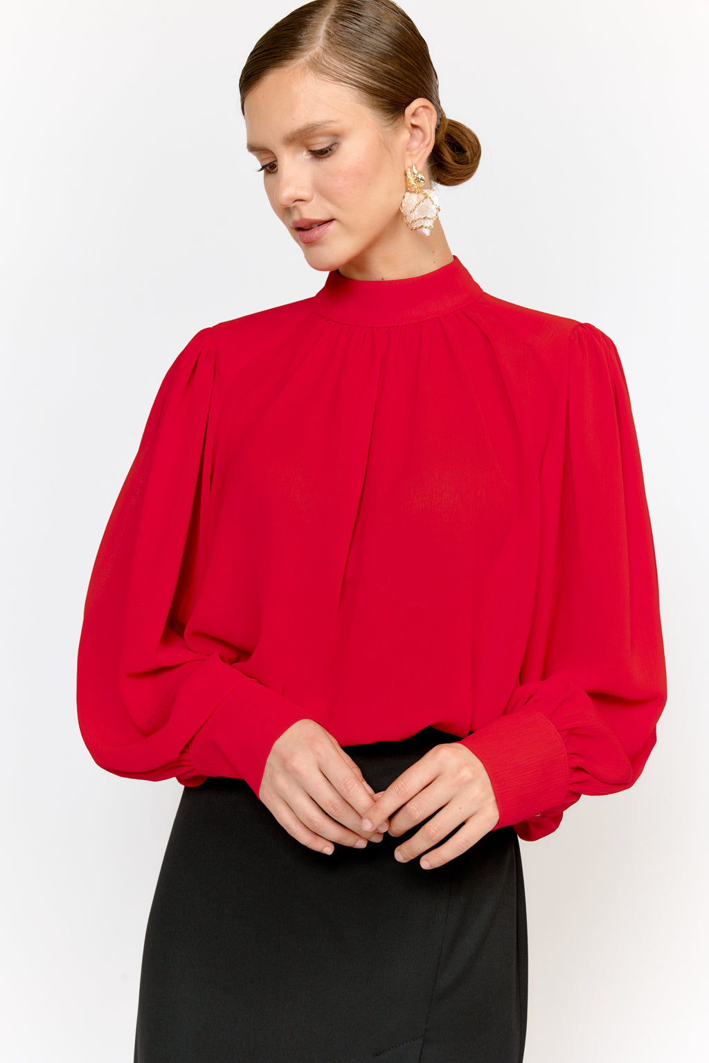 Woman wearing a red blouse with long sleeves against a white background
