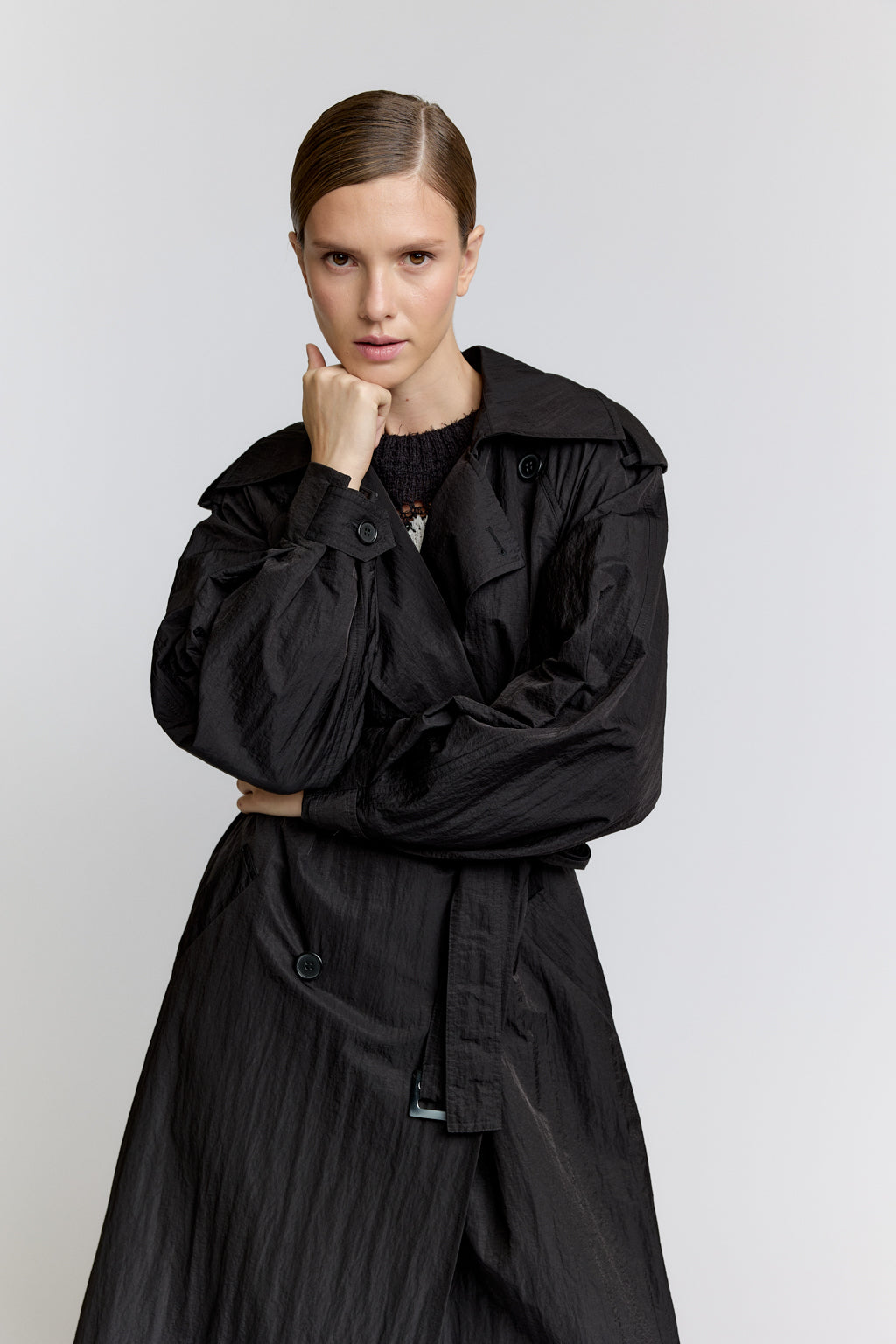 Person wearing a black coat against a plain background