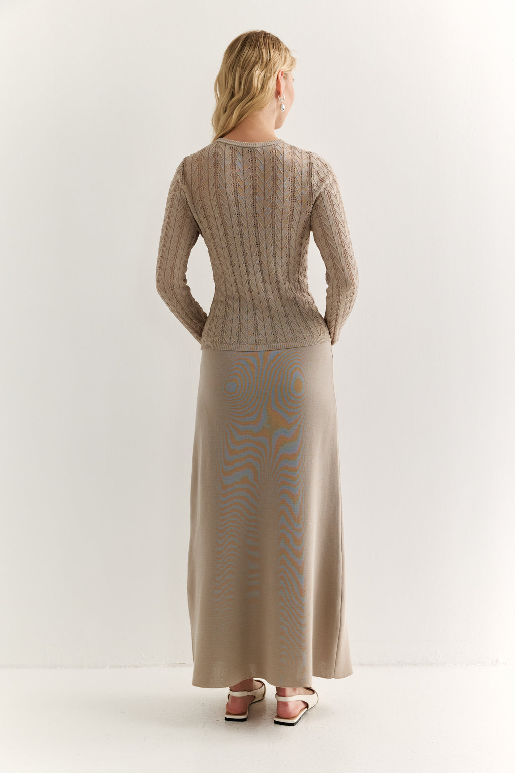 Woman wearing a beige knit dress with a plain white background