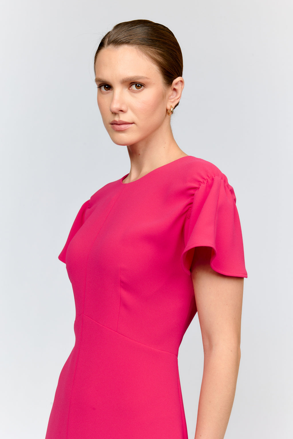 Woman wearing a bright pink dress against a light gray background