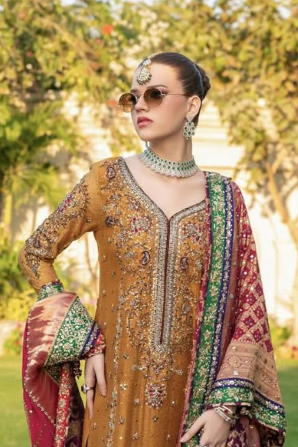 Woman in traditional embroidered outfit with sunglasses and jewelry outdoors