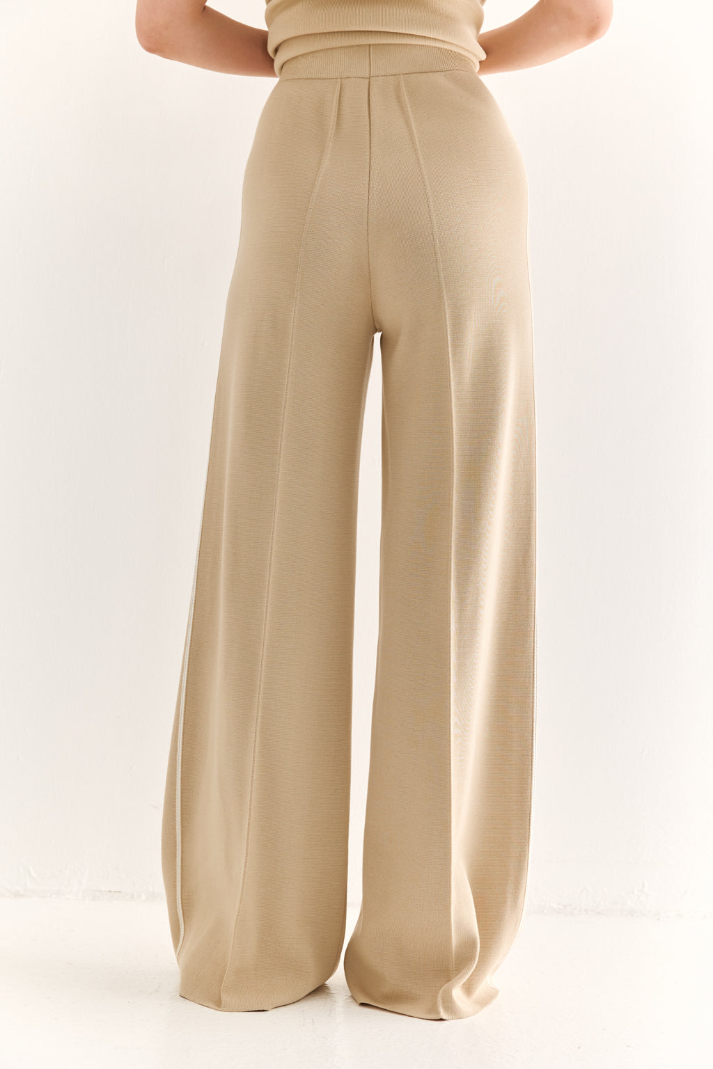 Beige wide-leg pants worn by a person on a white background