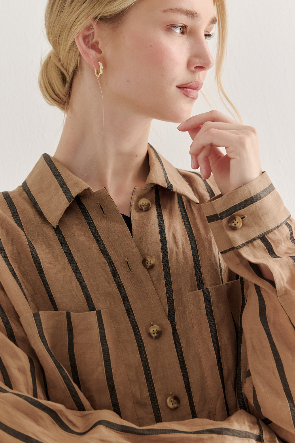Woman wearing a brown striped shirt with a neutral background
