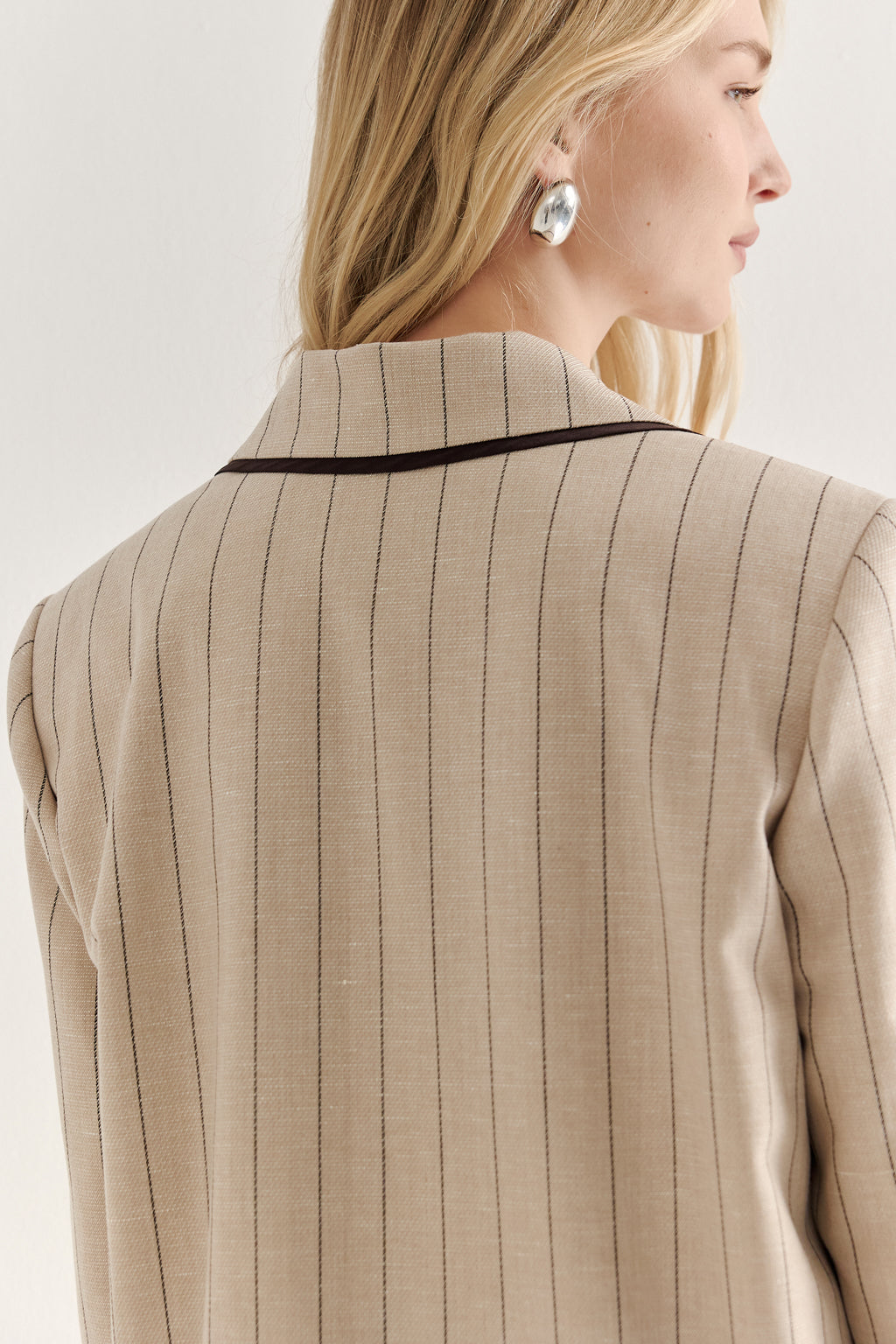 Beige pinstripe suit jacket worn by a person on a light background