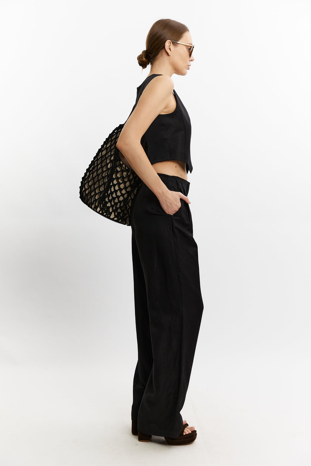 Woman wearing a black outfit with a textured bag on a white background