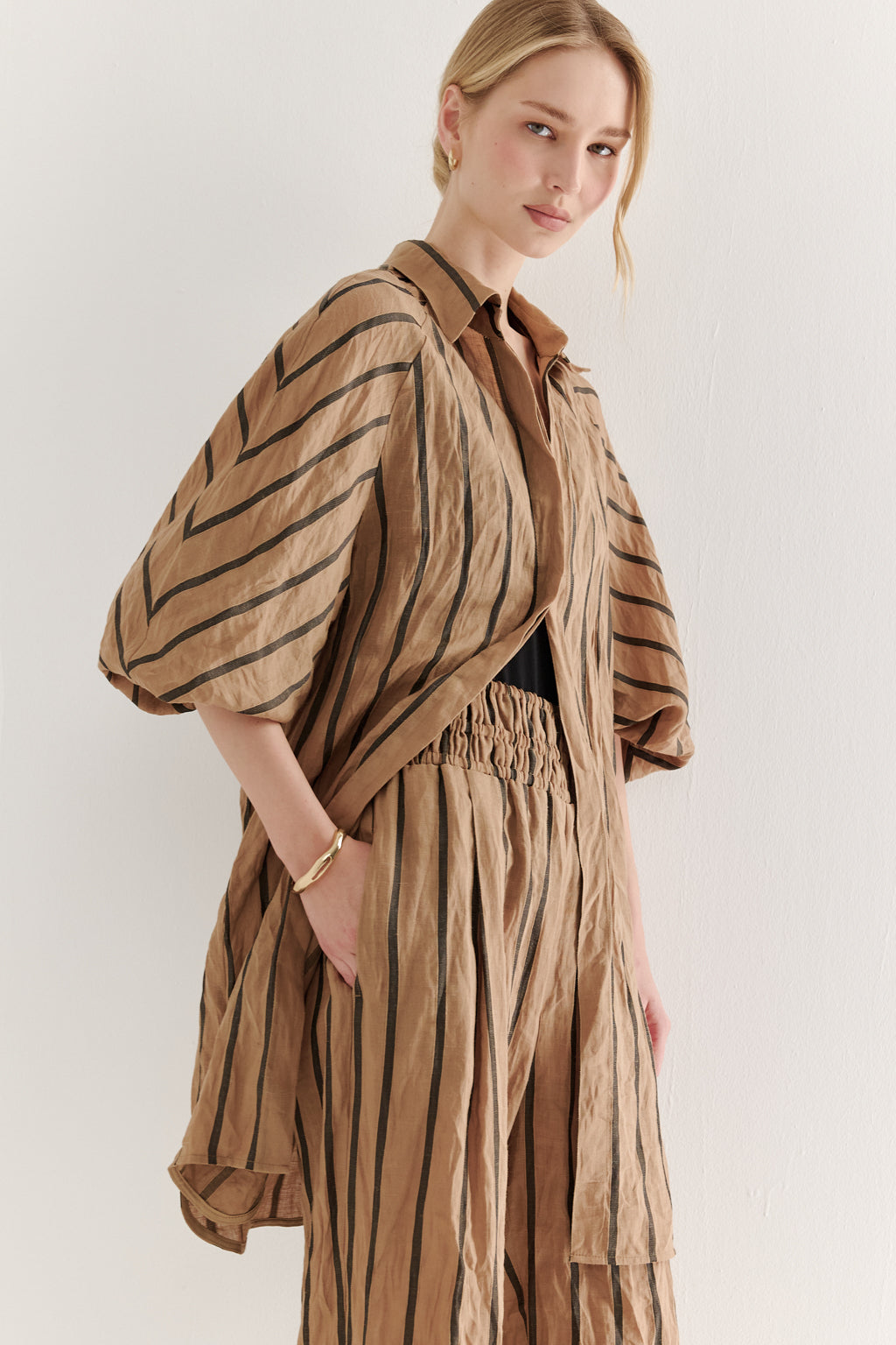 Woman wearing a brown striped outfit against a white background