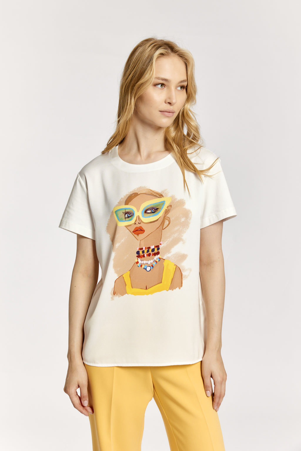 Woman wearing a white t-shirt with a graphic design on a plain background