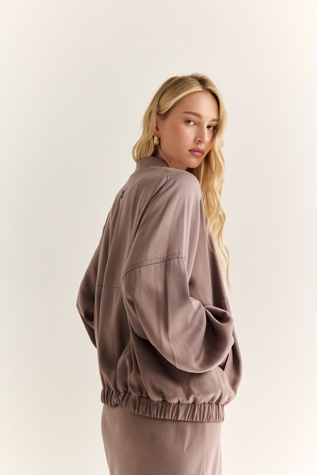 Woman wearing a brown jacket and pants on a light background